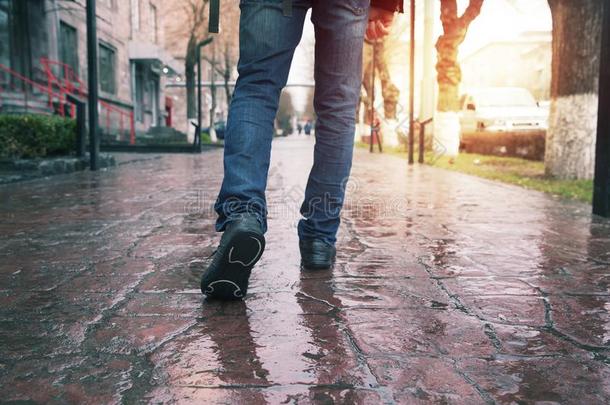 男人牛仔裤和橡皮底帆布鞋鞋子步行向人行道