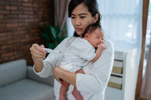 亚洲人母亲量温度向她小的婴儿