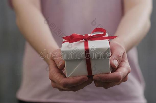 年幼的女人<strong>台</strong>和给看白色的赠品盒和红色的带弓