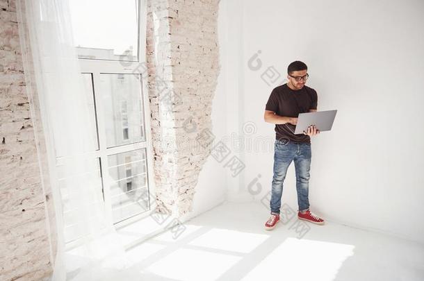 英俊的年幼的男人和便携式电脑和检查他的交通工具的运行时间表向白色的