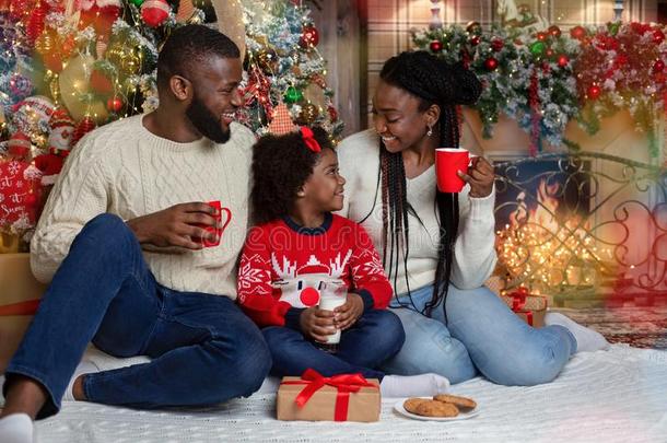 快乐的非洲式发型家庭喝饮料奶和吃甜饼干,庆祝