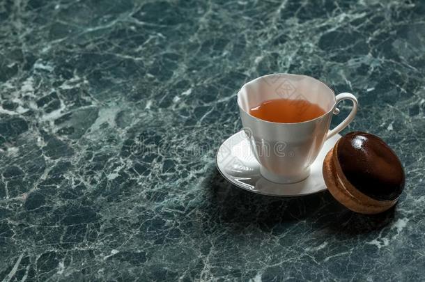 灌木蛋糕和白色的杯子关于黑的茶水和茶杯托向绿色的马布