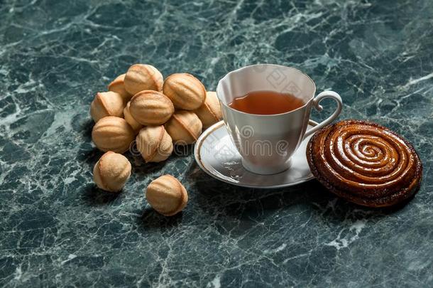 樟属植物圆形的小面包或点心和茶杯托,黑的茶水和饼干胡桃向大理石