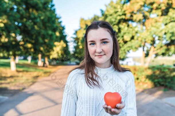 十几岁的青少年女孩夏,她手红色的心,白色的暖和的毛衣向