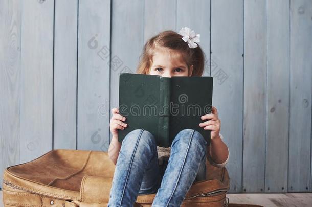 准备好的向大的旅行.幸福的小的女孩阅读令人感兴趣的书