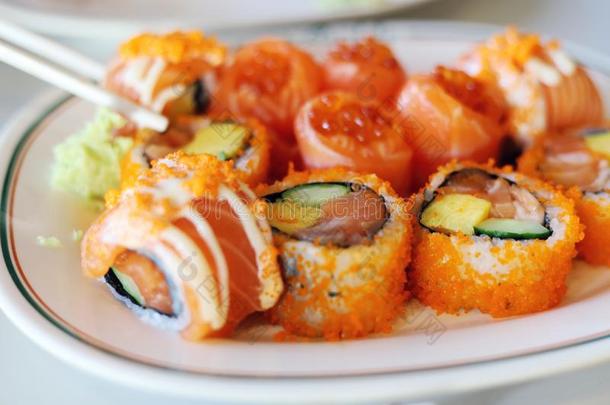 关-在上面桔子颜色鲑鱼寿司向白色的盘子.
