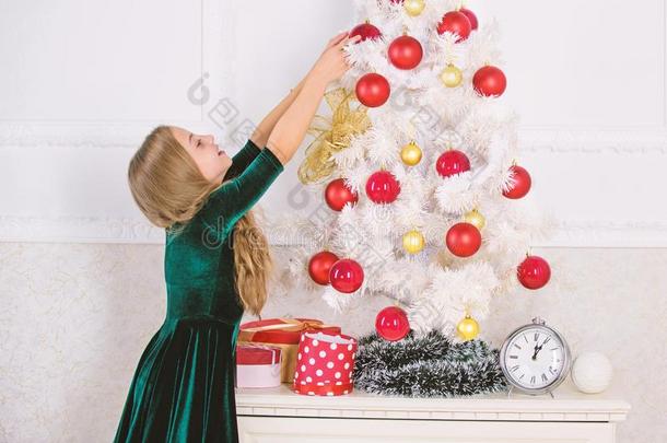 小孩悬挂圣诞节装饰球向人造的树.小孩aux.能够
