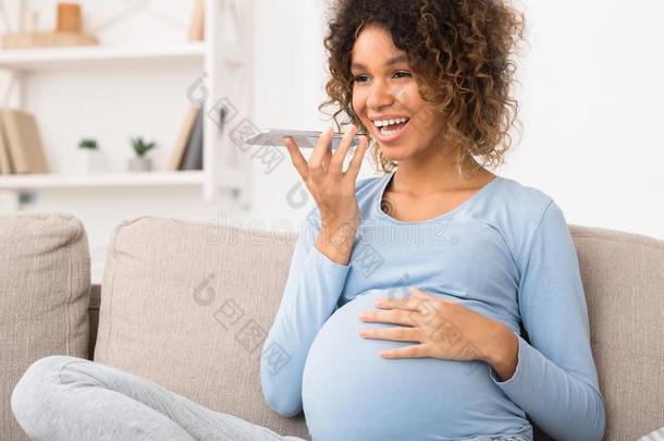 幸福的怀孕的女人发送嗓音信息向ph向e