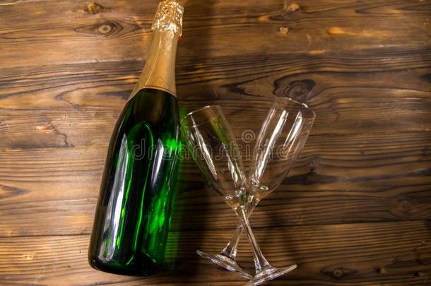 香槟酒瓶子和两个空的香槟酒眼镜向木制的后面