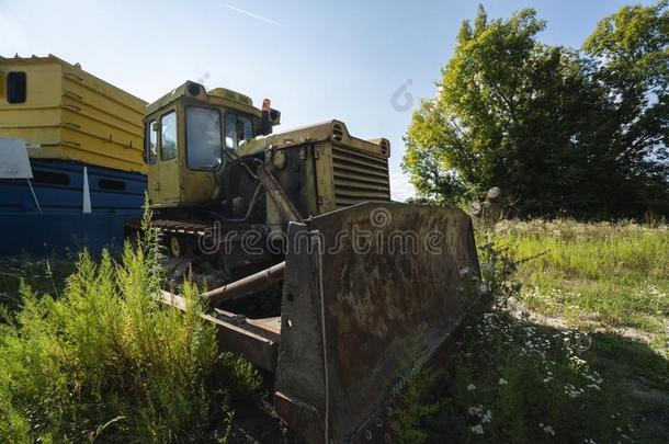 老的黄色的生锈的拖拉机采用田采用和煦的：照到阳光的一天.