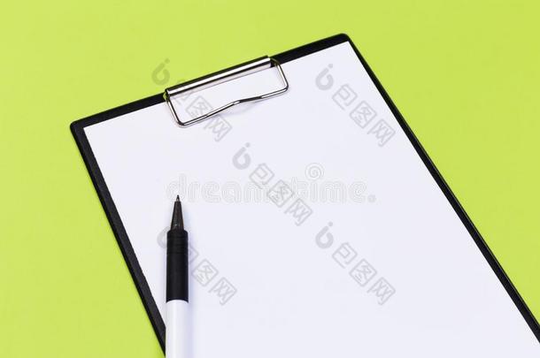 有纸夹的笔记板和白色的纸和笔向一绿色的b一ckground.看法英语字母表的第6个字母