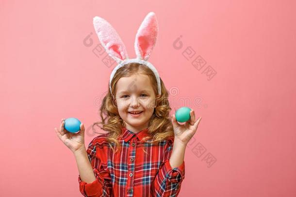 欢乐的小的小孩女孩和兔子耳和两个复活节卵