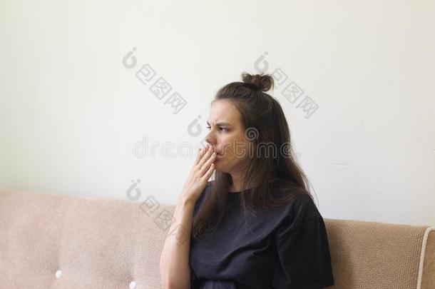 恶心的年幼的女人坐在家和一疼痛的thro在一nd咳嗽