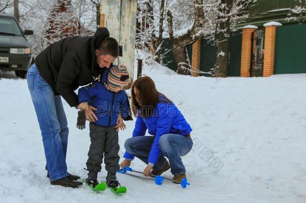 妈妈和爸爸帮助他们的儿子放向滑雪板.冬娱乐关于