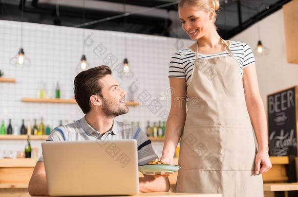 快乐的美好的女服务员带来食物