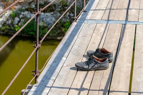 穿旧的老的黑的皮擦靴人面看法向木制的桥
