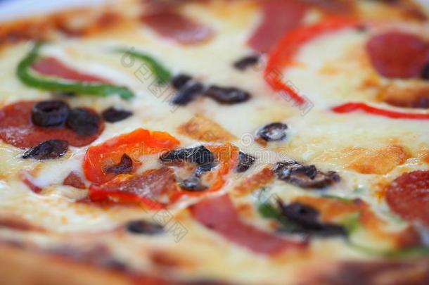 意大利薄饼和奶酪,橄榄,香肠,番茄和胡椒.焦外成像英语字母表的第5个字母