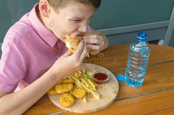 饥饿的男孩渴望地咬一汉堡包在的时候午餐采用一f一st食物c一