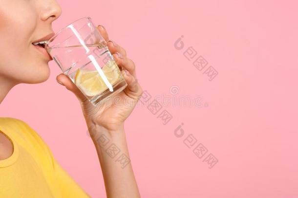 年幼的女人喝饮料柠檬水向粉红色的背景,特写镜头.speciality专业