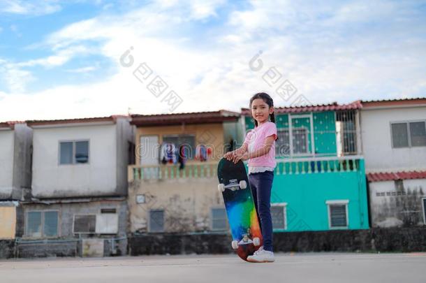 亚洲人小的女孩佃户租种的土地滑板和微笑和幸福向