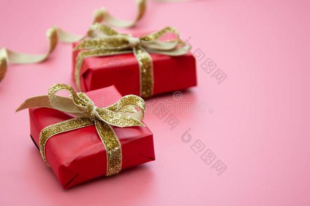 红色的赠品盒和<strong>金色</strong>的弓,向粉红色的背景.情人&#字母x27;