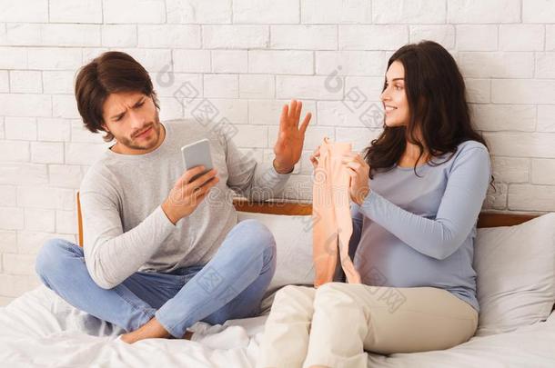 漠不关心的丈夫不顾他的怀孕的妻子,使用智能手机