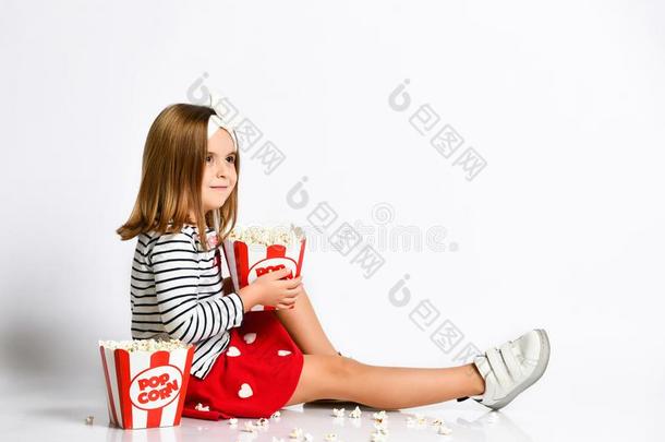 年幼的小的女孩采用一红色的裙子坐向指已提到的人地面和一水桶