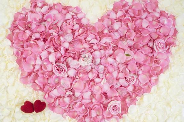 两个红色的心向粉红色的玫瑰花瓣