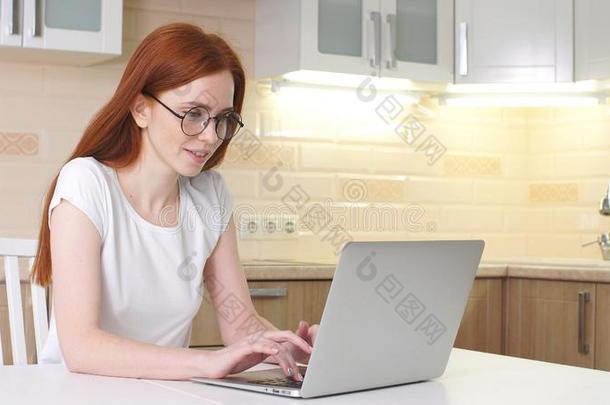 年幼的美丽的女人微笑的和工作的和计算机在家