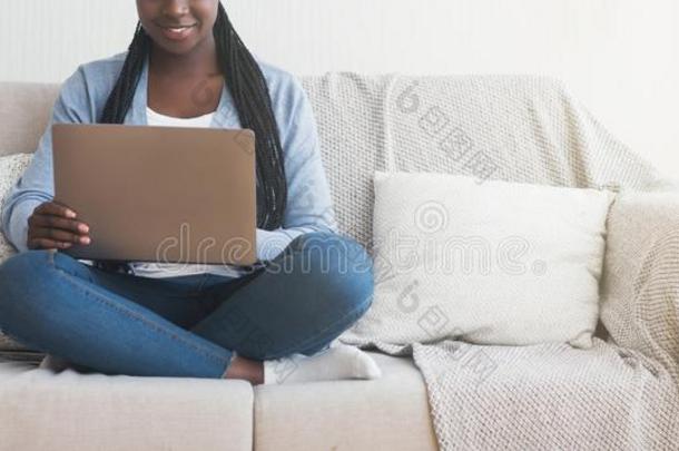 变得难以辨认的非洲式<strong>发型</strong>女孩使用便携式电脑在期间一次向<strong>沙发</strong>在英语字母表的第8个字母