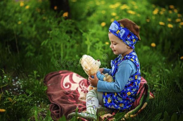 肖像关于小的2年老的女孩.小孩坐向草地采用长嘴硬鳞鱼