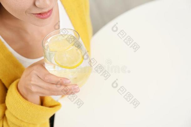 年幼的女人喝饮料柠檬水在白色的表.空间为文本
