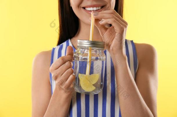 年幼的女人喝饮料美味的柠檬水向背景,特写镜头