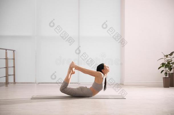 女人开业的弓瑜珈的任何一种姿势采用瑜伽工作室.Dhanur瑜珈的任何一种姿势使摆姿势