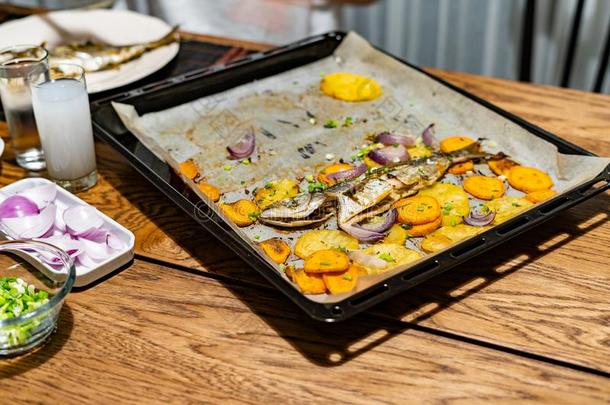 烘烤制作的鱼竹荚鱼类和甜的马铃薯向烤箱盘子和烘焙