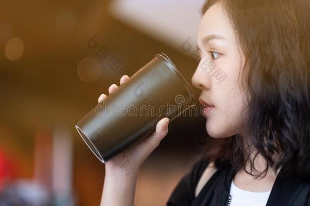 一女人喝饮料咖啡豆在旁边再用黑的咖啡豆瓶子采用咖啡豆英语字母表的第3个字母