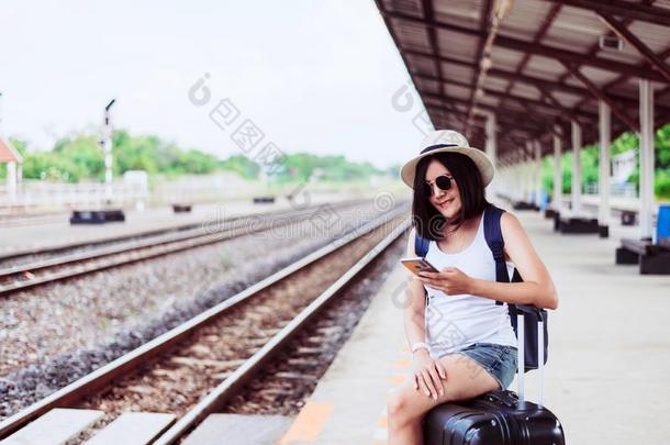 幸福的亚洲人女人旅行者使用可移动的电话和便携式电脑计算