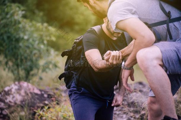 关在上面关于手男人获得帮助向最好的朋友攀登一岩石,他