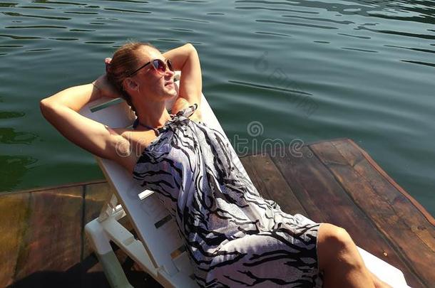 女人躺向一太阳灯浴浴床采用sungl一sses一nd一波希米亚式的丝sh一wl.女孩