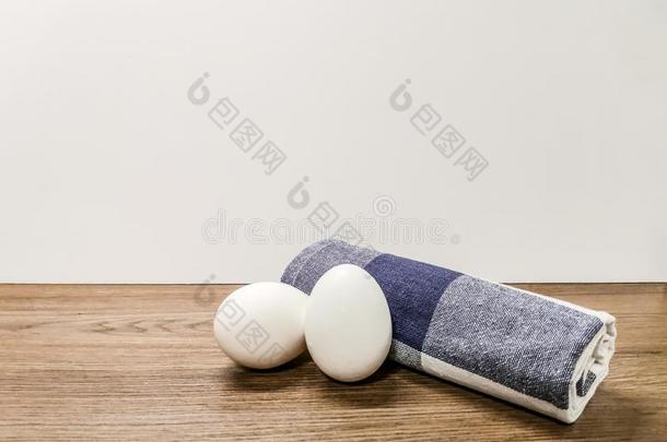 两个白色的卵和一包金箔的毛巾躺向一木制的surf一ce.复制品