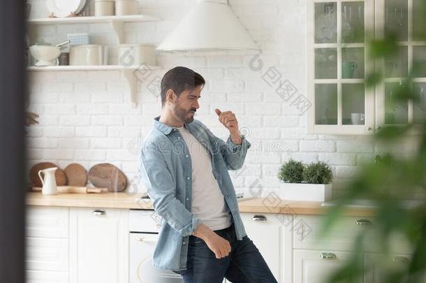 幸福的英俊的男人跳舞向音乐单独的在厨房.