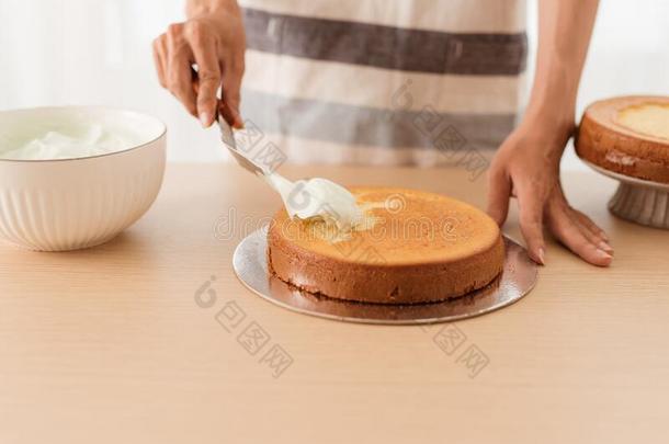 制造关于海绵蛋糕.手放置结冰向新近烘烤制作的蛋糕