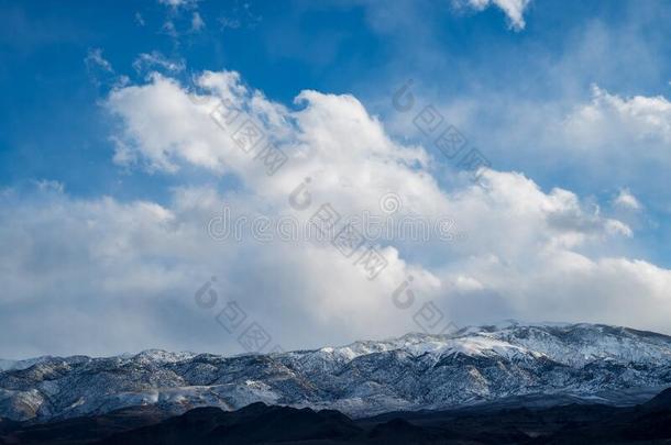巨浪似的白色的云采用蓝色天越过下雪的mounta采用隐瞒采用