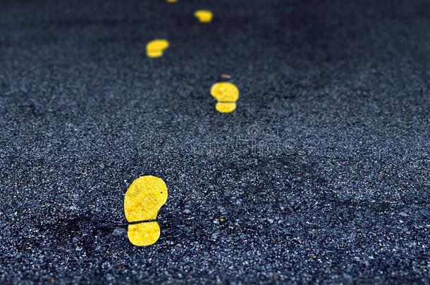 黄色的脚印手势向一沥青路.描画的脚印sint.安静