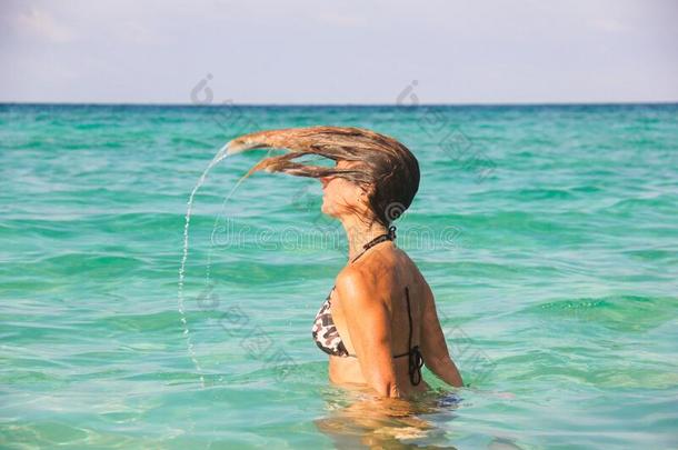 比基尼式游泳衣女人使溅起水和头发向后的