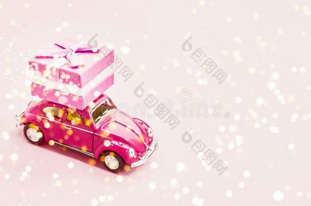 粉红色的制动火箭玩具汽车递<strong>送赠品</strong>盒向粉红色的背景.2月