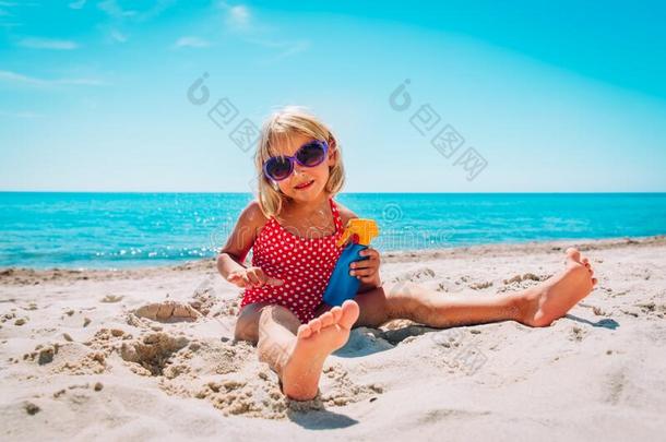 太阳保护-漂亮的小的女孩和防晒霜在海滩
