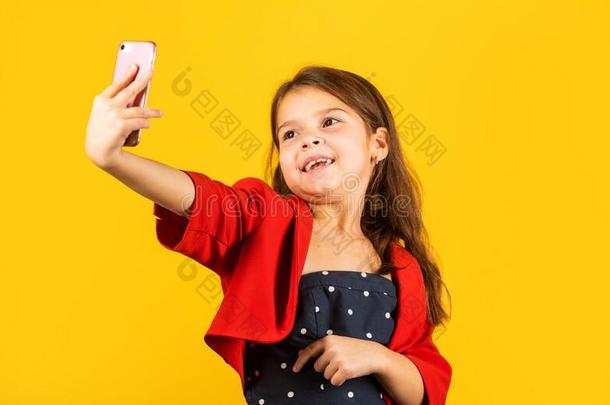 自拍照时间.小的女孩拿自拍照和智能手机黄色的后面