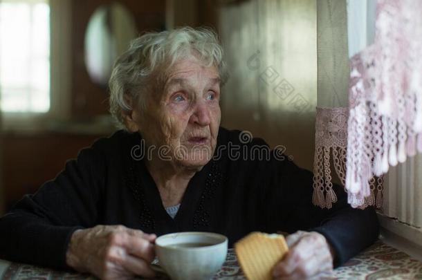 一上了年纪的女士喝饮料茶水和甜饼干.