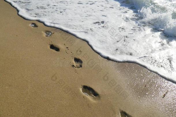 脚印和起泡沫向海滩